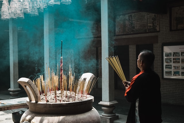 man standing holding incense sticks